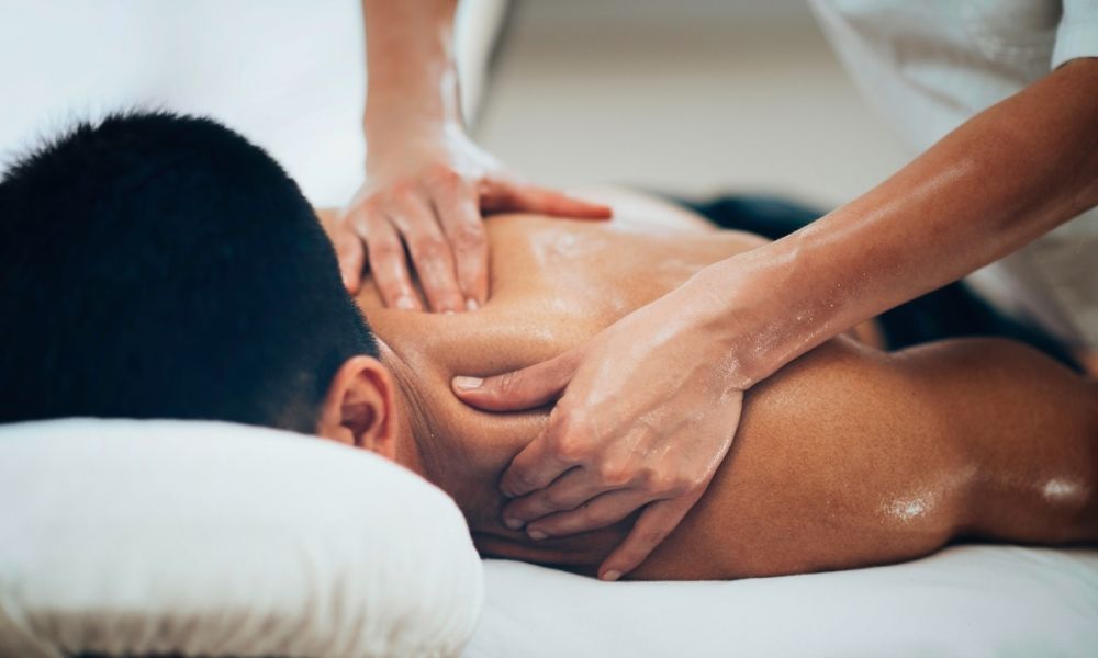 Caucasian male face down on massage table receiving a shoulder massage