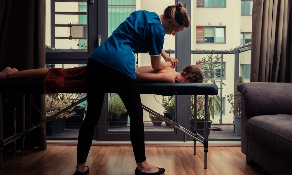 Massage therapist administering a massage inside the home of a client